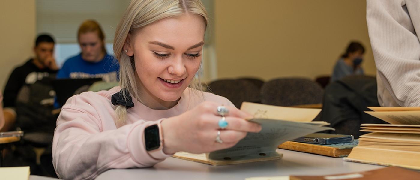 U N E student looking through historical paperwork